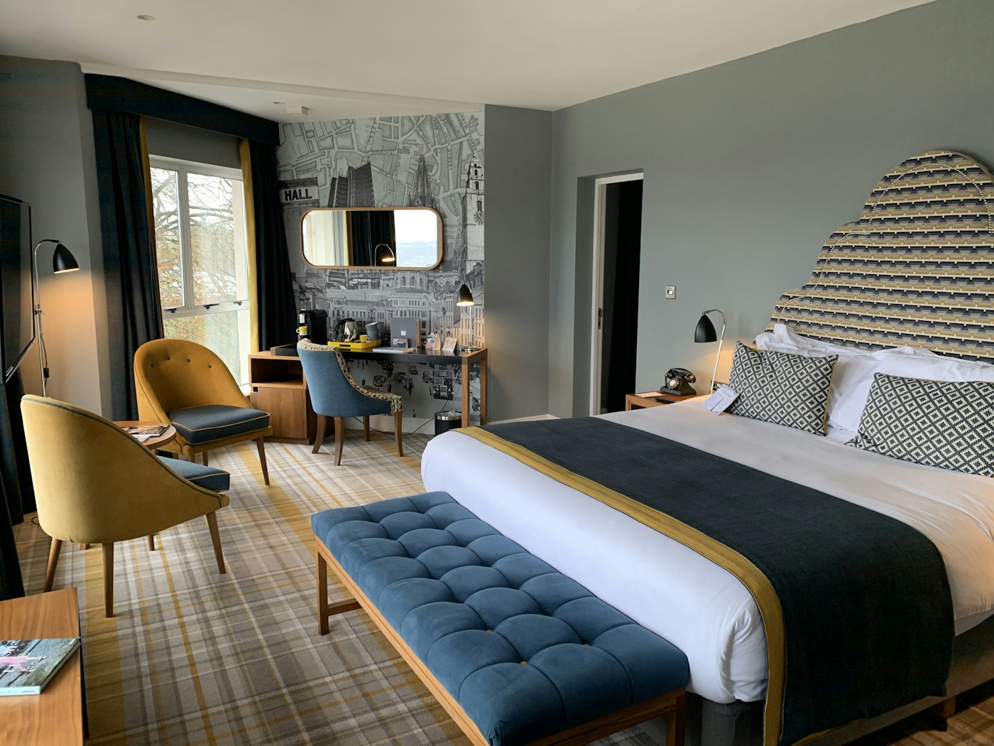 Spacious hotel room with a bed, armchair, and contemporary warm interior